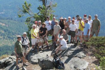 A group of hikers at the summit of a mountain in a redwood tree forest