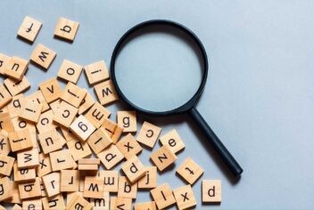 a magnifying glass on a blue surface with random scrabble game letter pieces