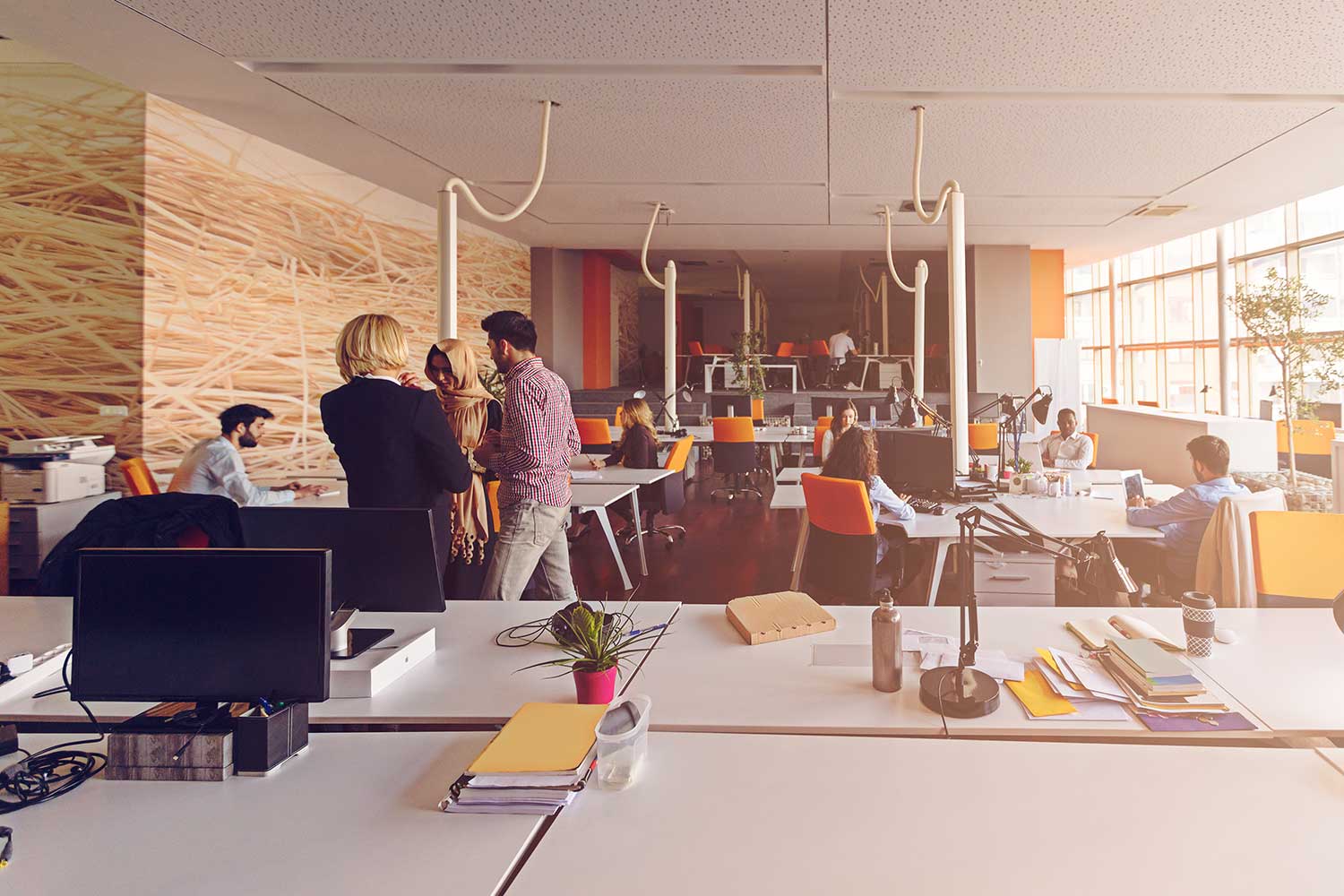 People are seen walking about an open-space work area in an office.