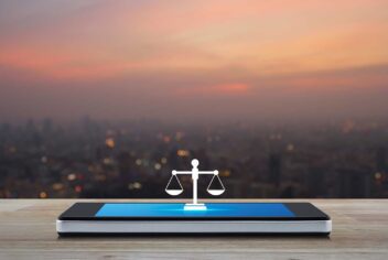 Flat law icon on modern smartphone screen on wooden table over blur of cityscape on warm light sundown.