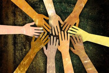 Stylized image of many different hands, of all different skin tones, reaching into the middle of the frame together.