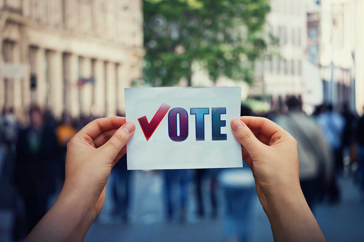 Hands hold a paper sheet with the message "vote"