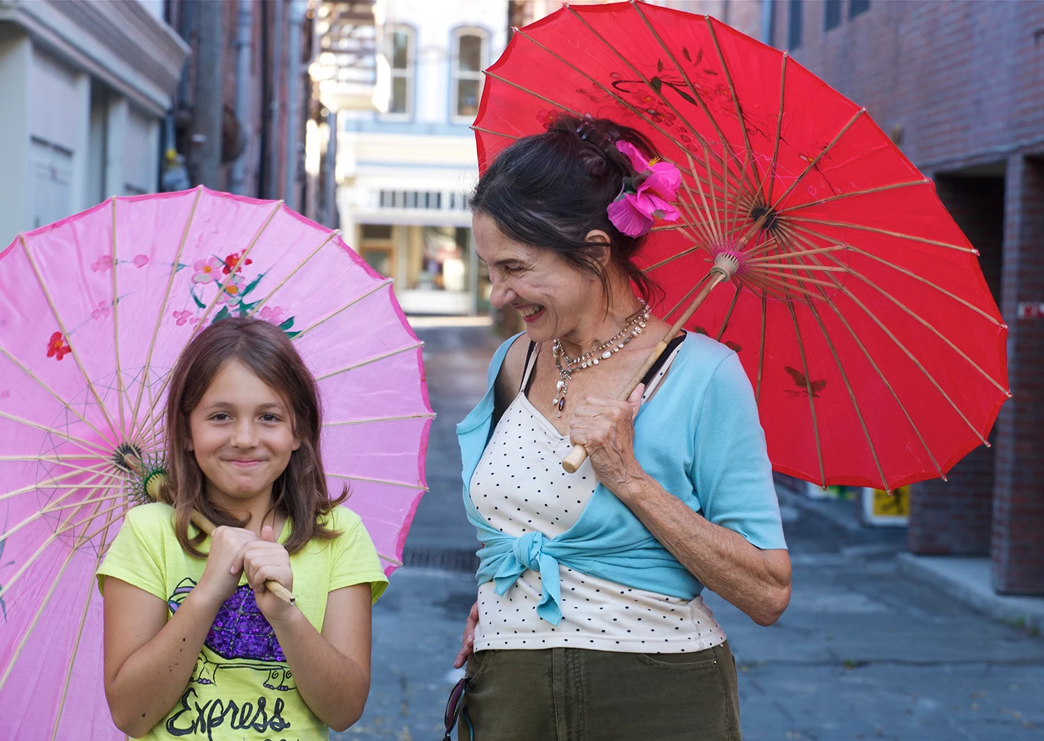 A woman and young girl have colorful parasols during the daytime.
