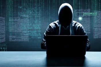 An illustration of a hooded man in shadows sitting at a laptop with a background of computer data