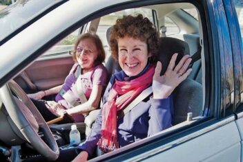 Two ladies in a car. The driver is waving to the camera.