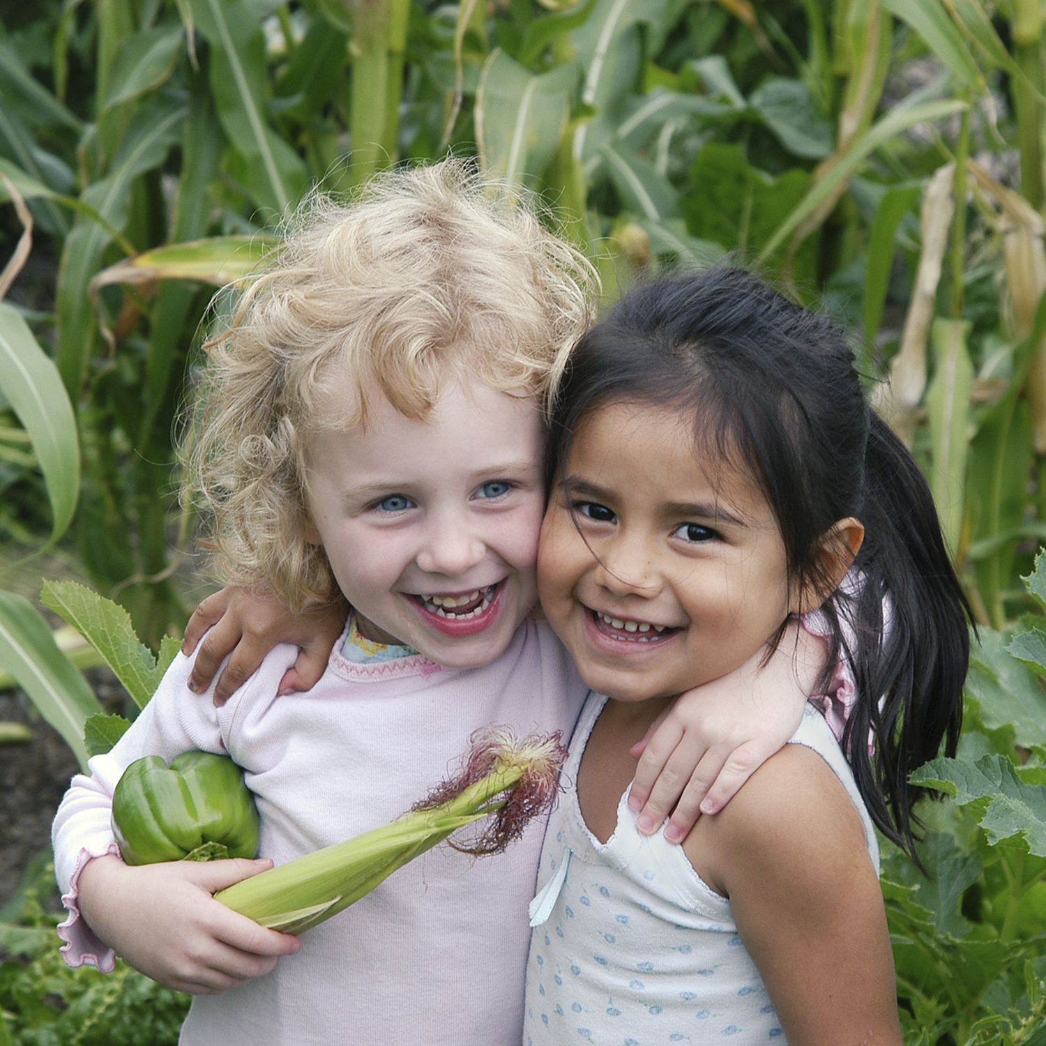 Two young children embrace as they pick veggies in the garden at North Bay Children's Center in Novato, CA