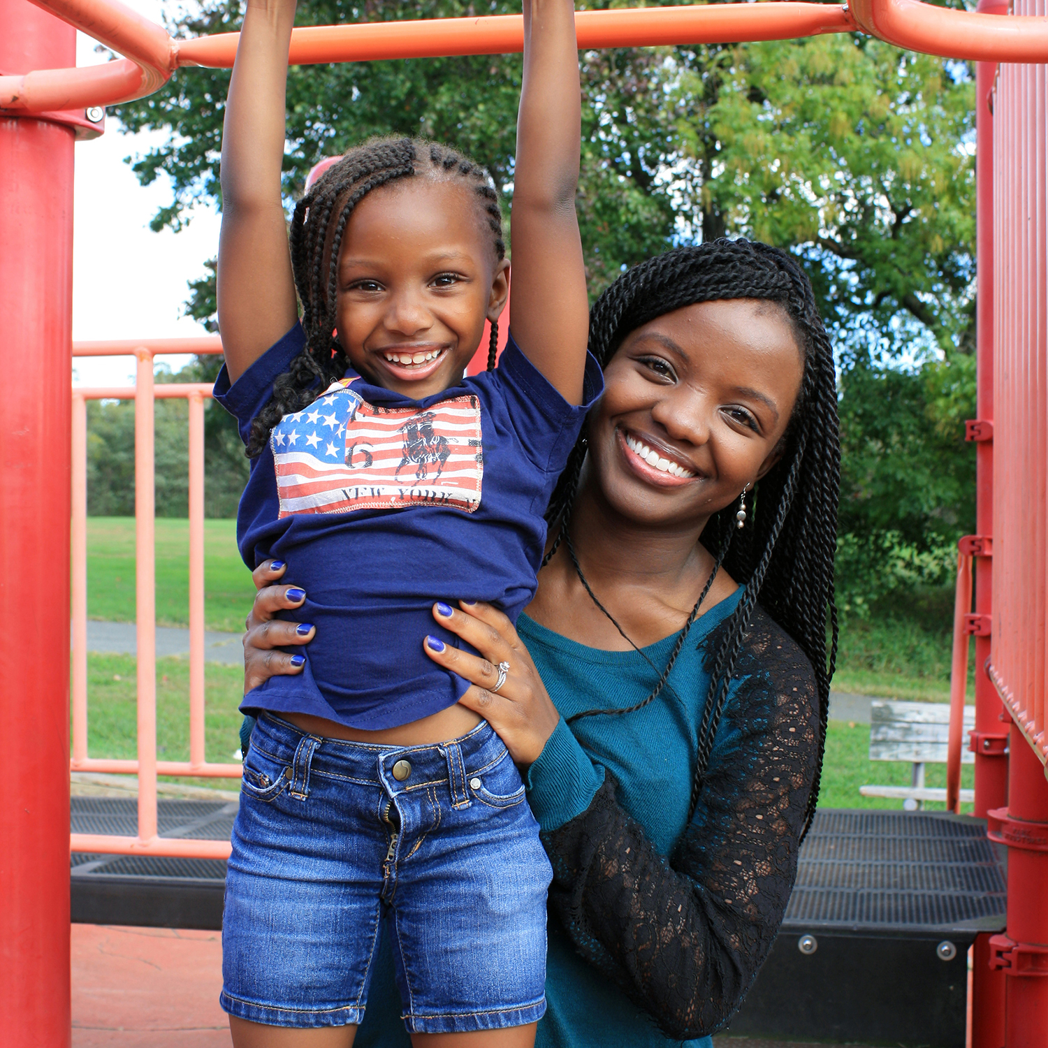 A woman holds a child on a play structure outside