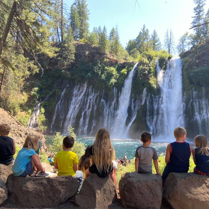 A group of children look at a waterfall