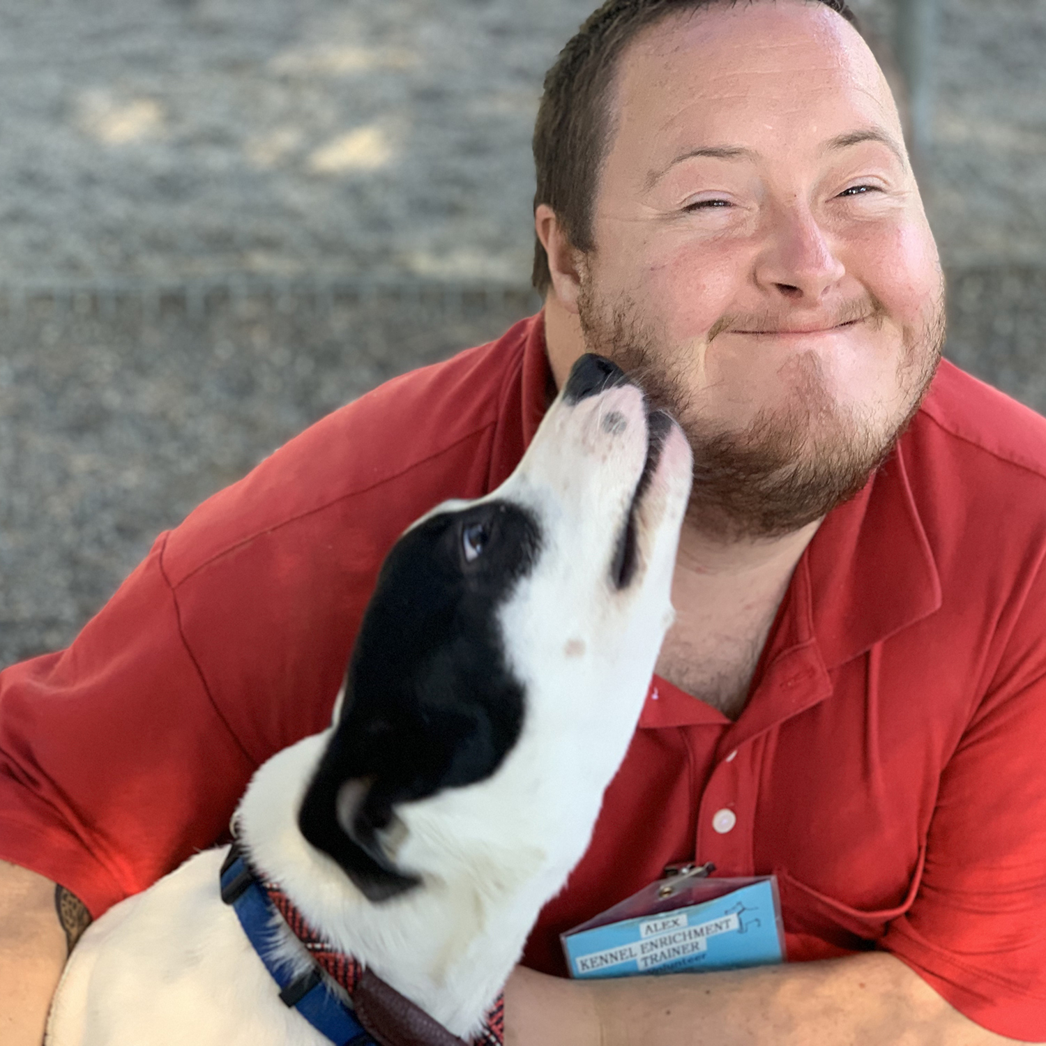 A young man smiles as a dog licks his face