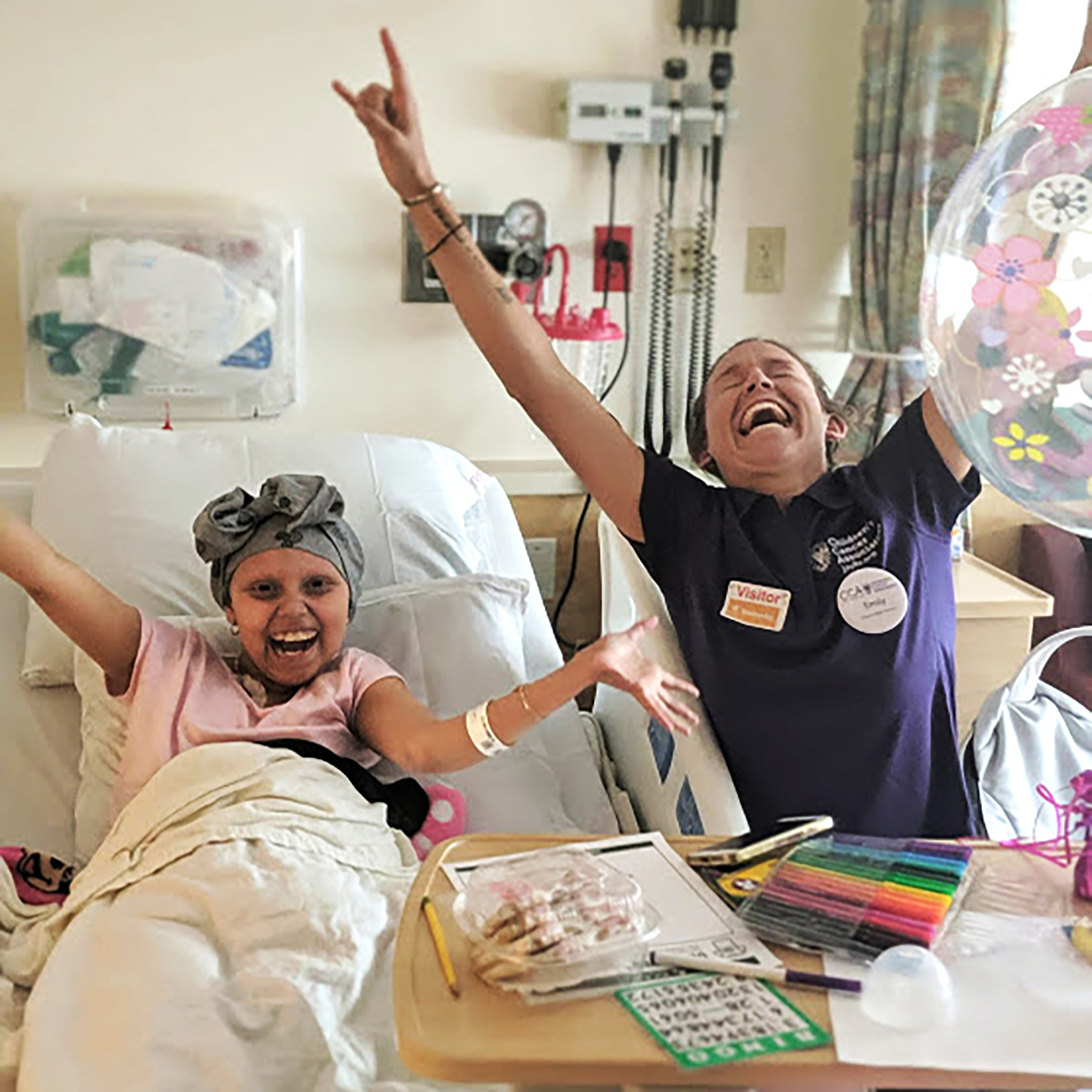 A hospital patient and a hospital worker celebrate with arms raised