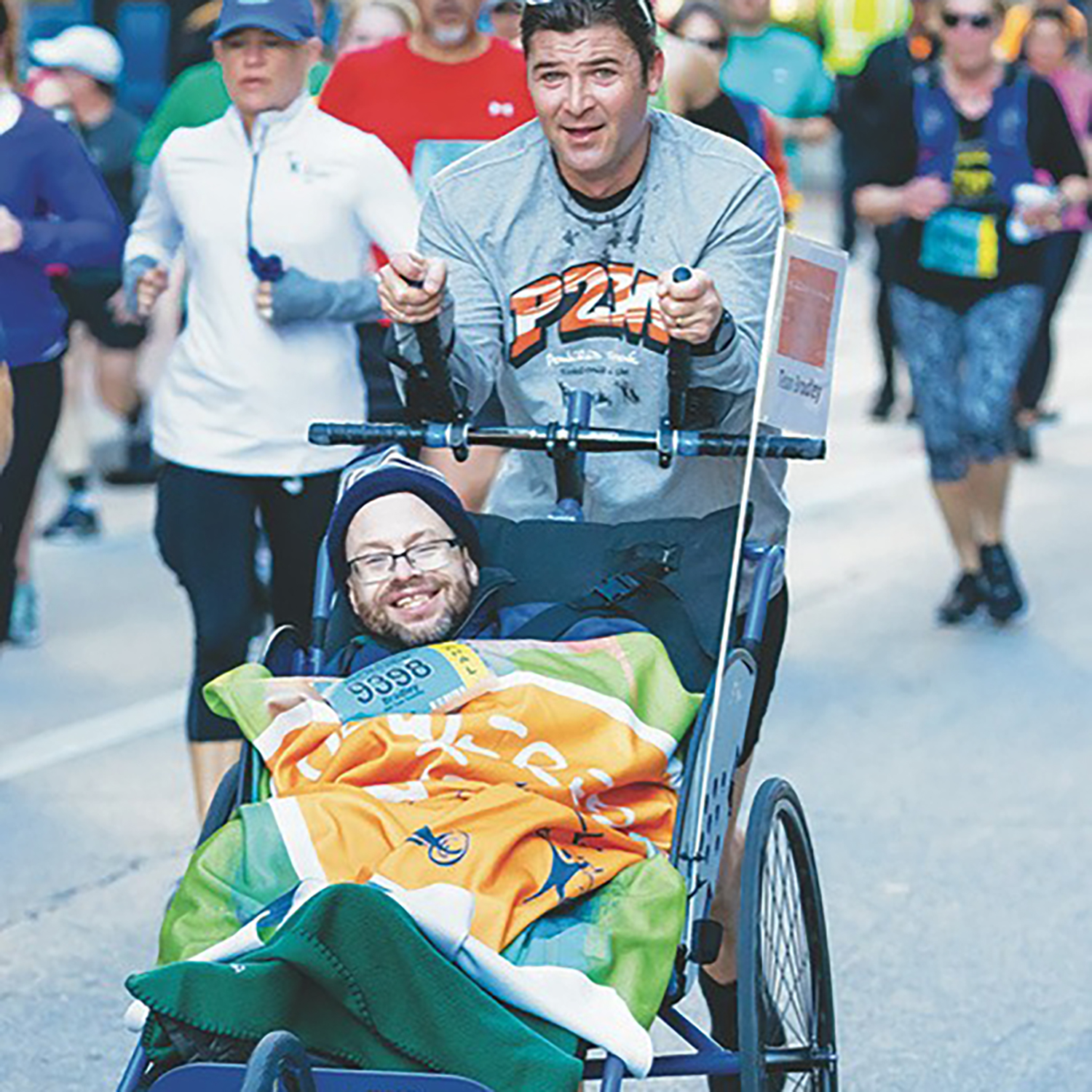 A runner pushes a person in a wheelchair in a group race