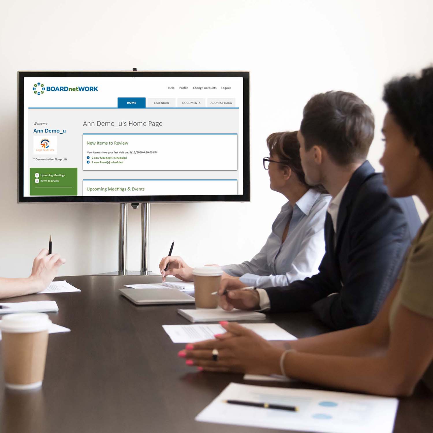 business people sitting at conference table look at a monitor on the wall