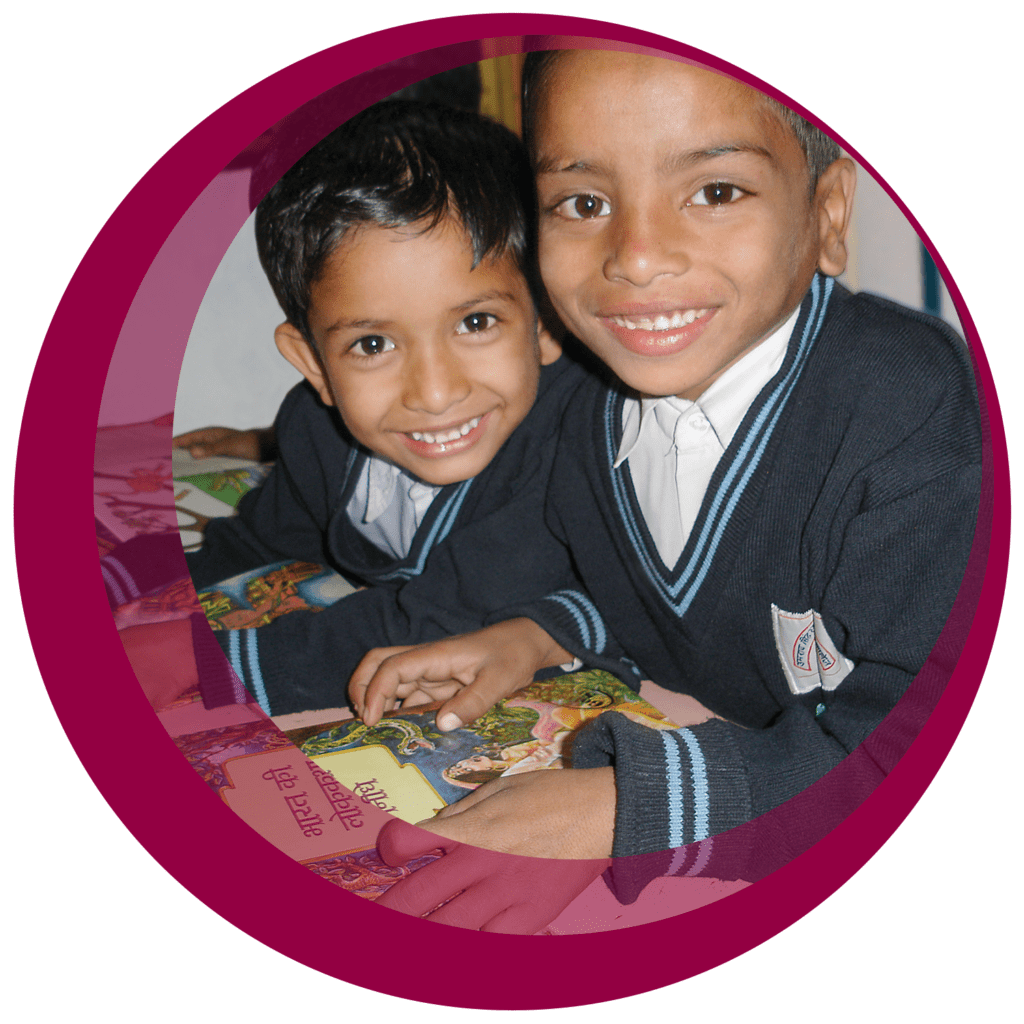Two smiling boys in school uniforms holding a book