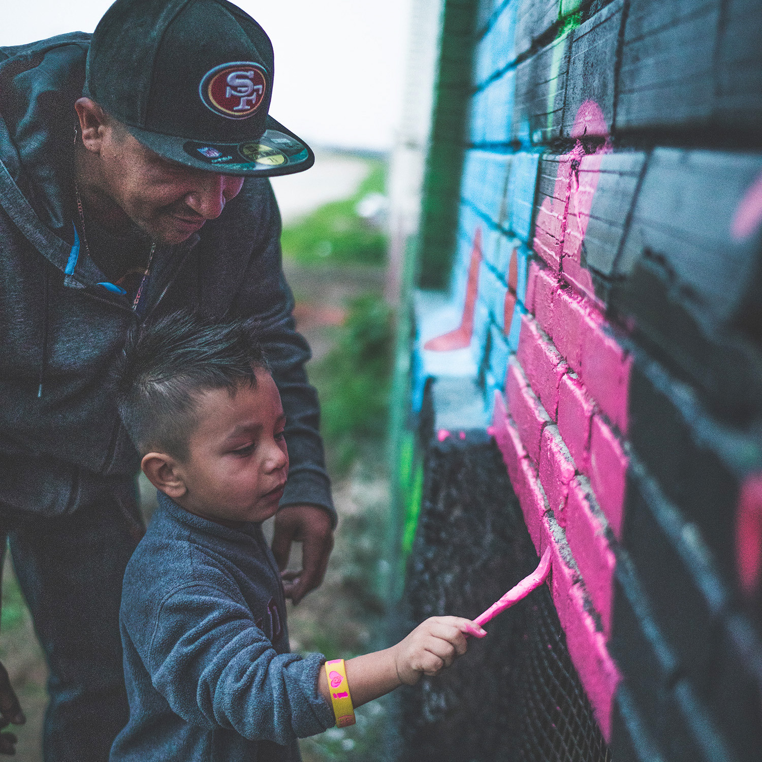 A man and a young boy paint a mural together