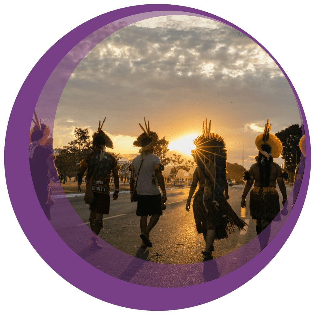 a group of people in native american attire walk toward a sunset