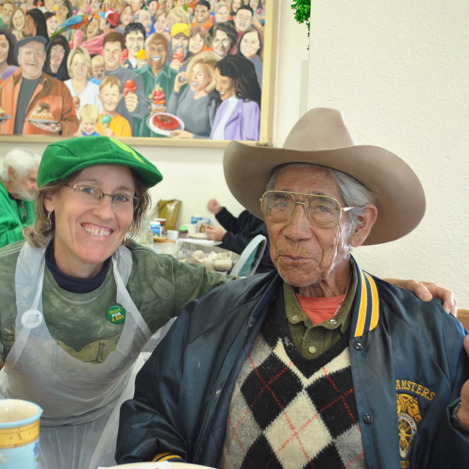 two people in hats pose in a cafeteria