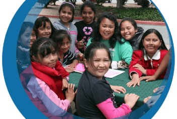 a group of girls sitting around an outdoor table with their teacher