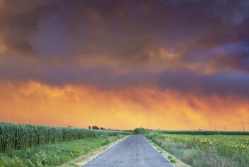 a rural road with storm clouds above