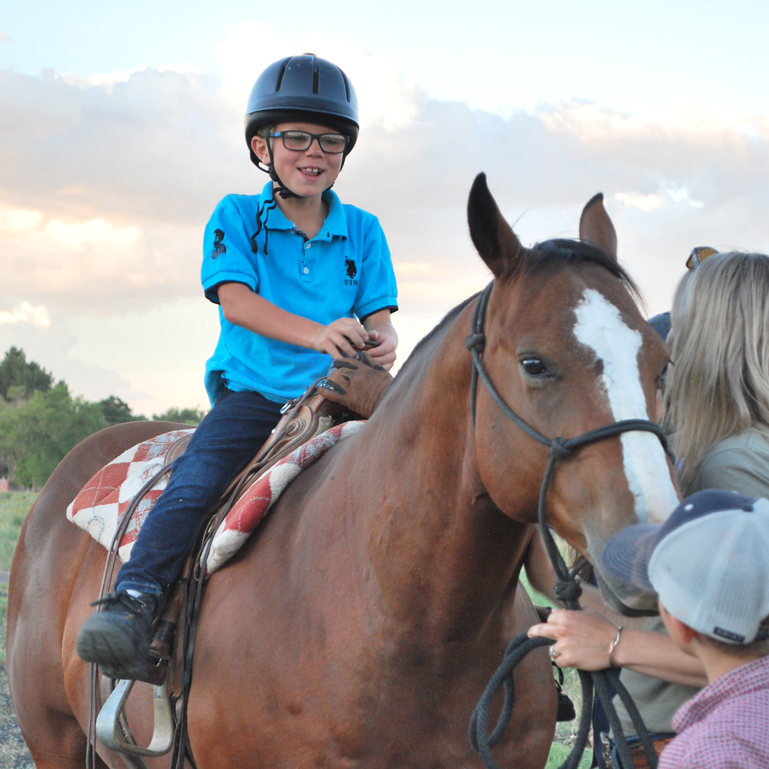 a boy in a helmet rides a horse