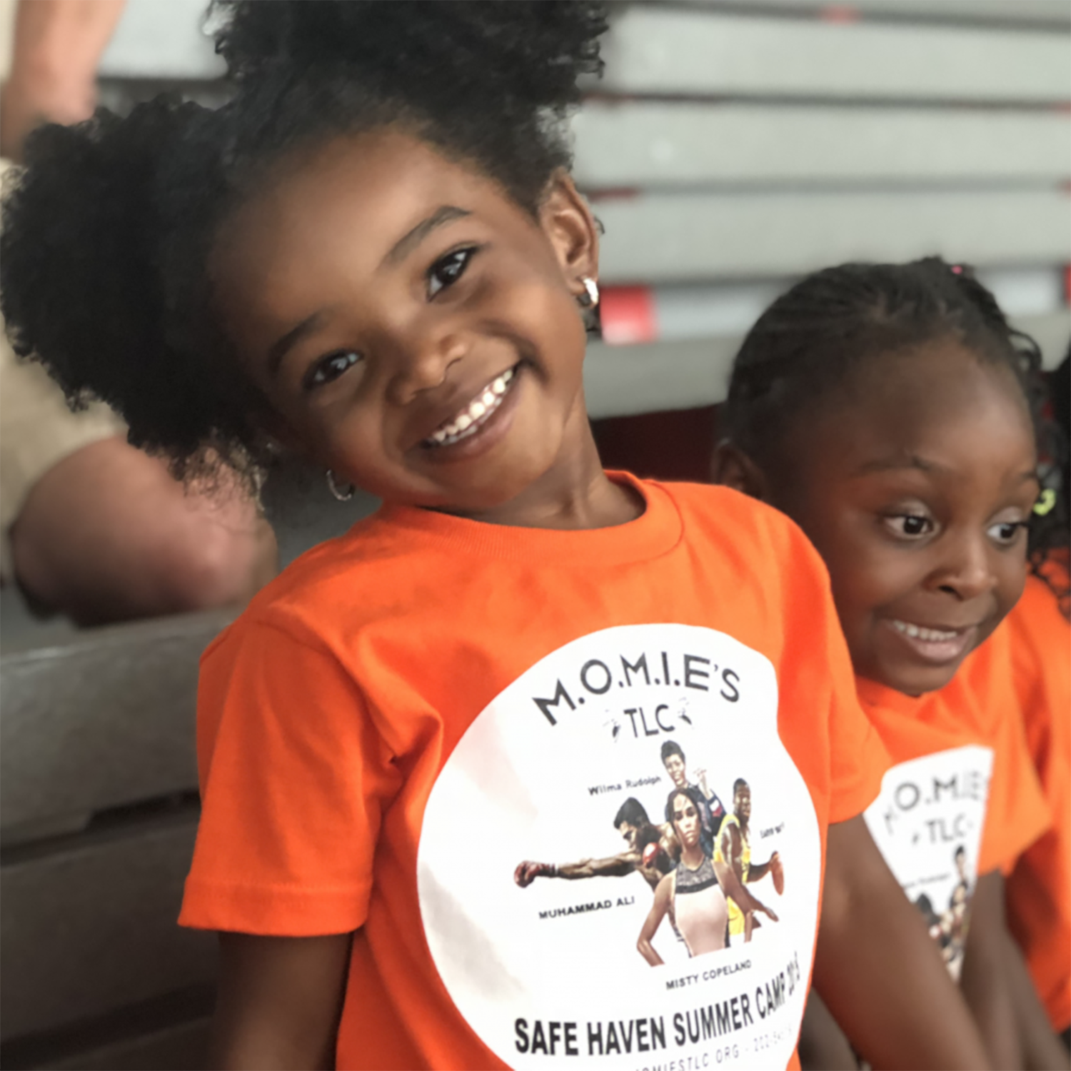 two smiling girls in orange t-shirts
