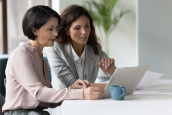 Two business women looking at a laptop together