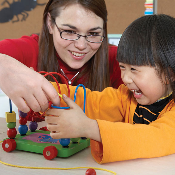 a woman helps a child with a learning toy