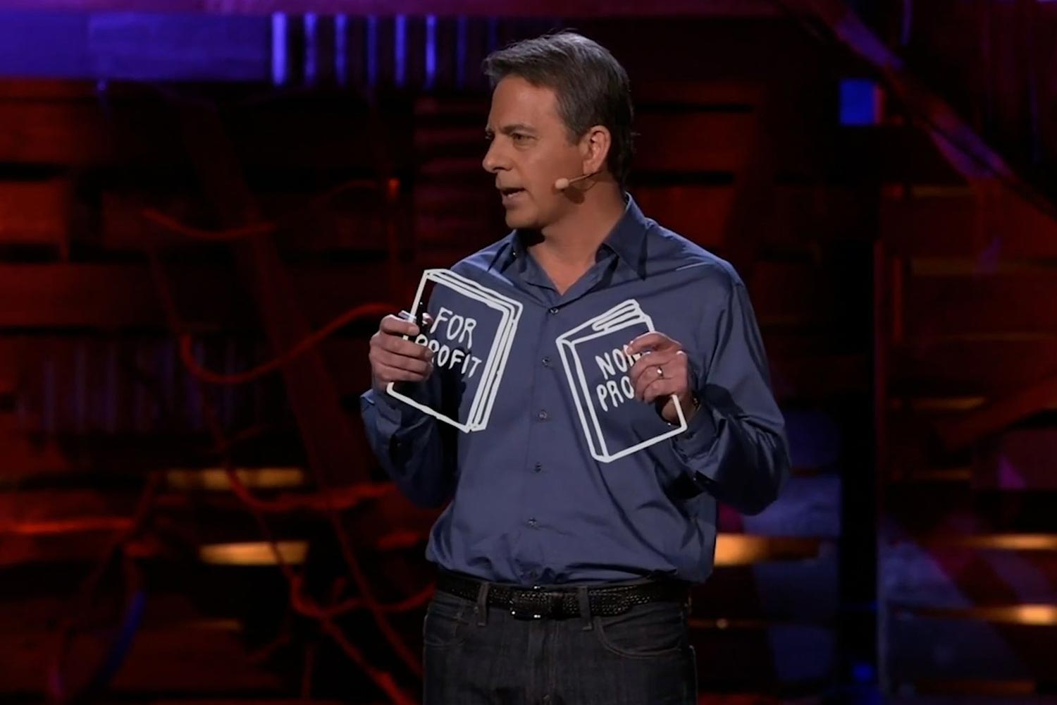 Dan Pallotta gives a TED Talk. Two books are animated into his hands, one titled For Profit, the other titled Non Profit