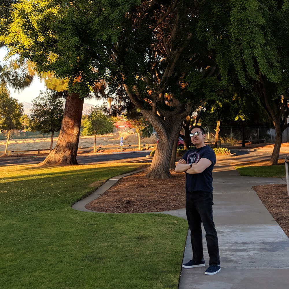 Navin L. standing on a sidewalk near grass and trees