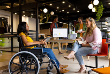 a group of people in a modern office setting with one wheelchair