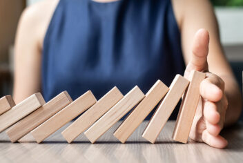 a person's hand stops a row of falling small wood pieces