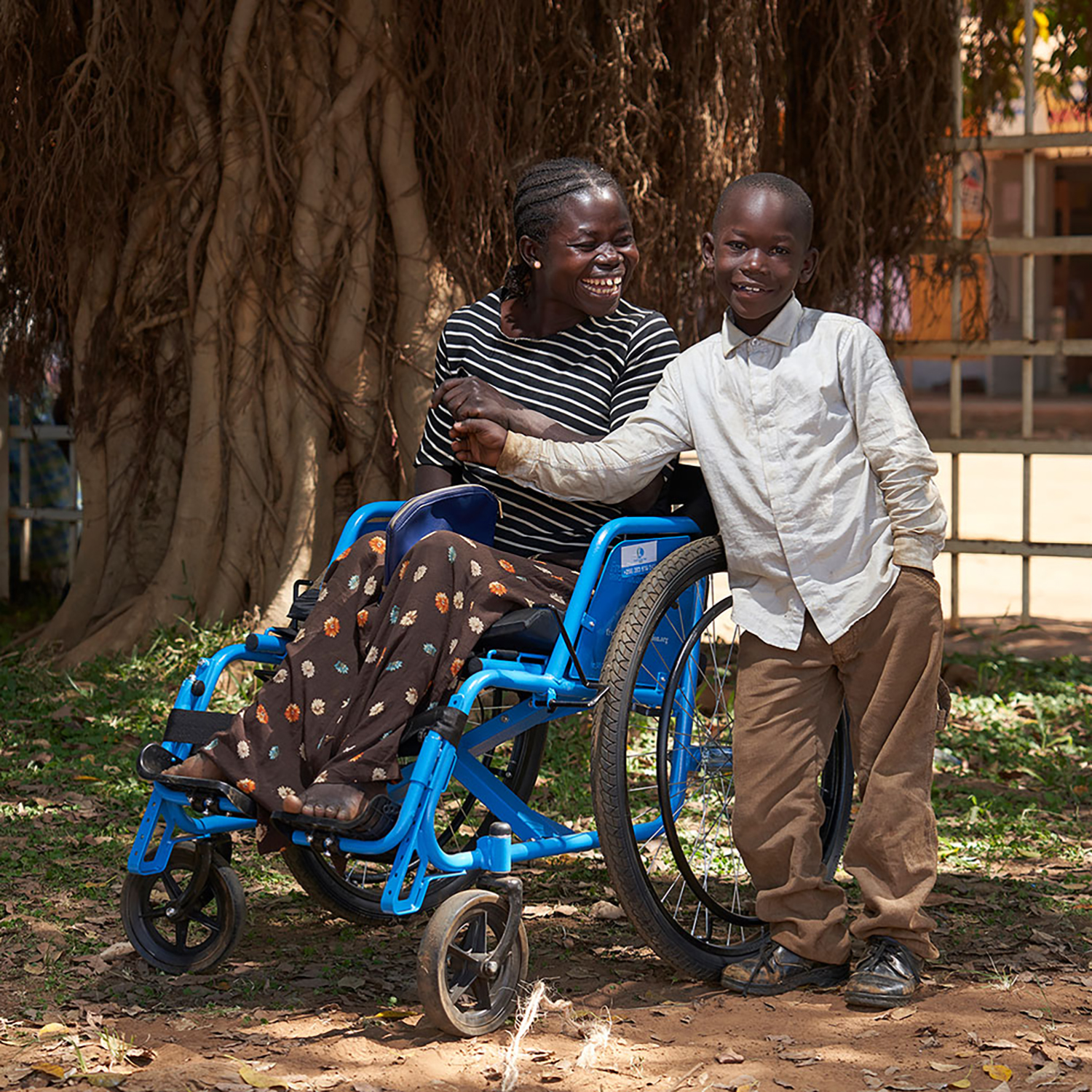 a woman sitting in a wheelchair with a boy standing