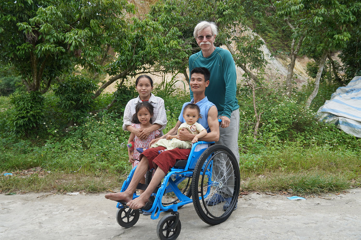 a man in a wheelchair holding a baby with three other people