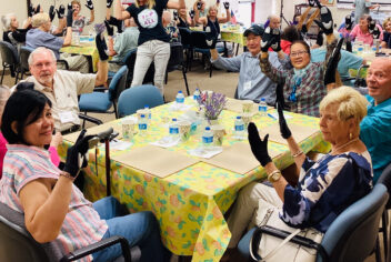 people sitting around tables holding their hands up