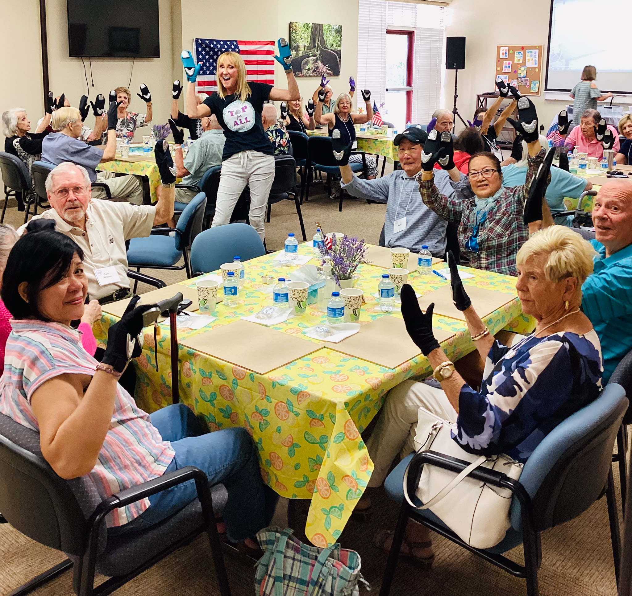 people sitting around tables holding their hands up