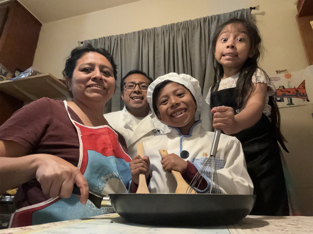 four people in a kitchen cooking together