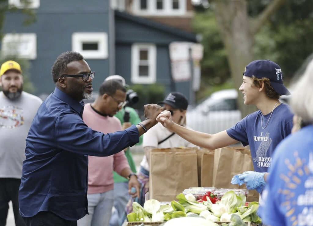 fist bump of two people over a table for food distribution