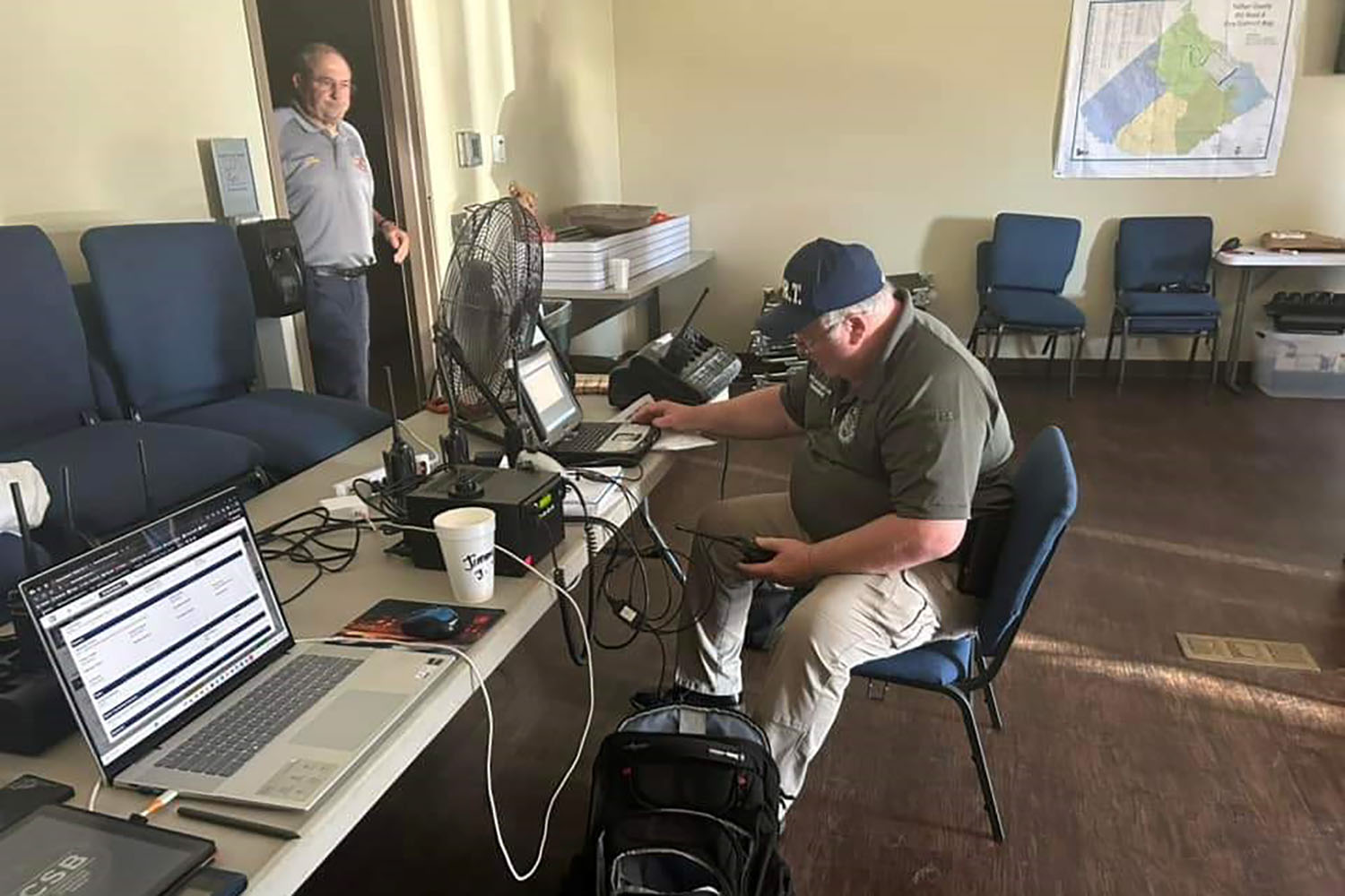 two men in a room with laptops and radios