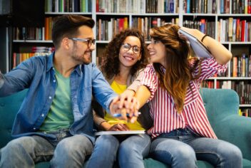 three people sitting on a couch in a library