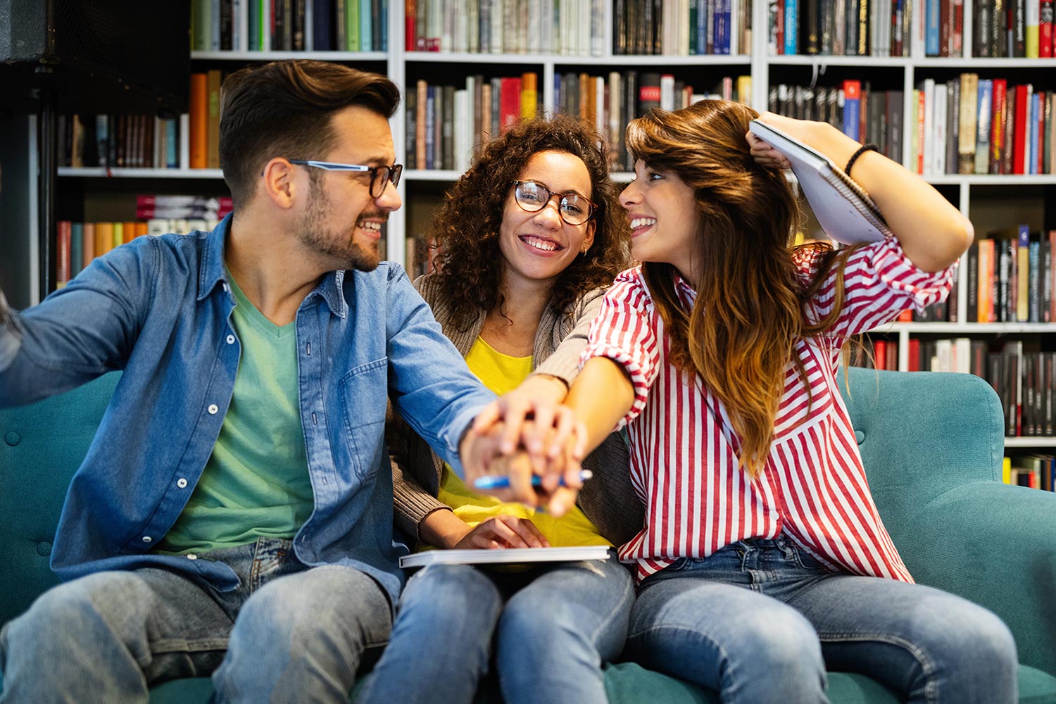 three people sitting on a couch in a library