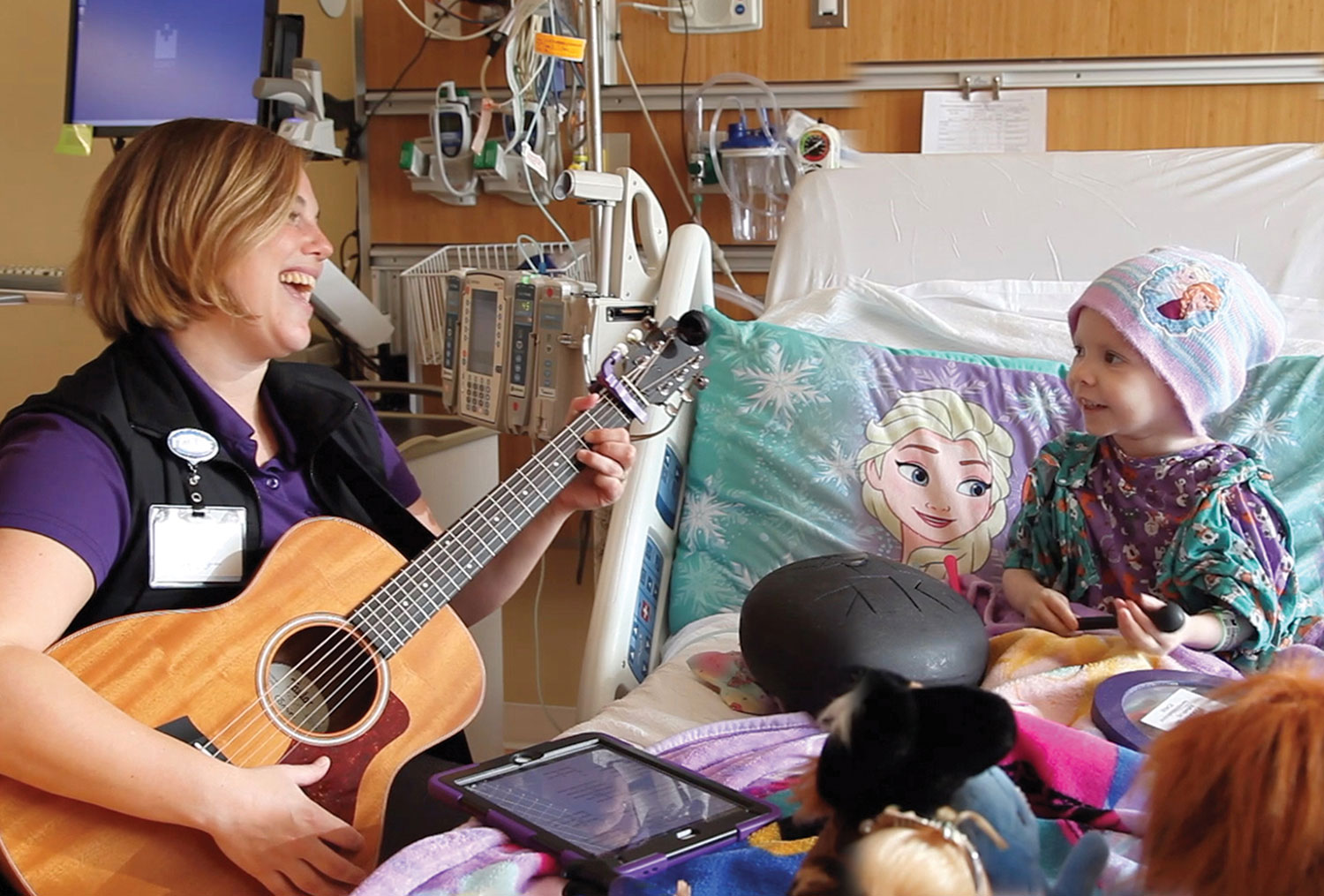 a woman playing guitar for a child in the hospital