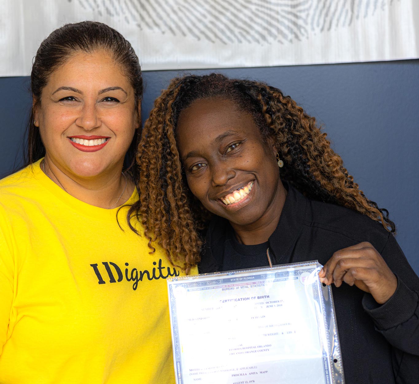 two people holding a birth certificate in front of an IDignity thumbprint sign