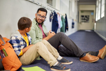 a man and boy sitting in a hallway talking