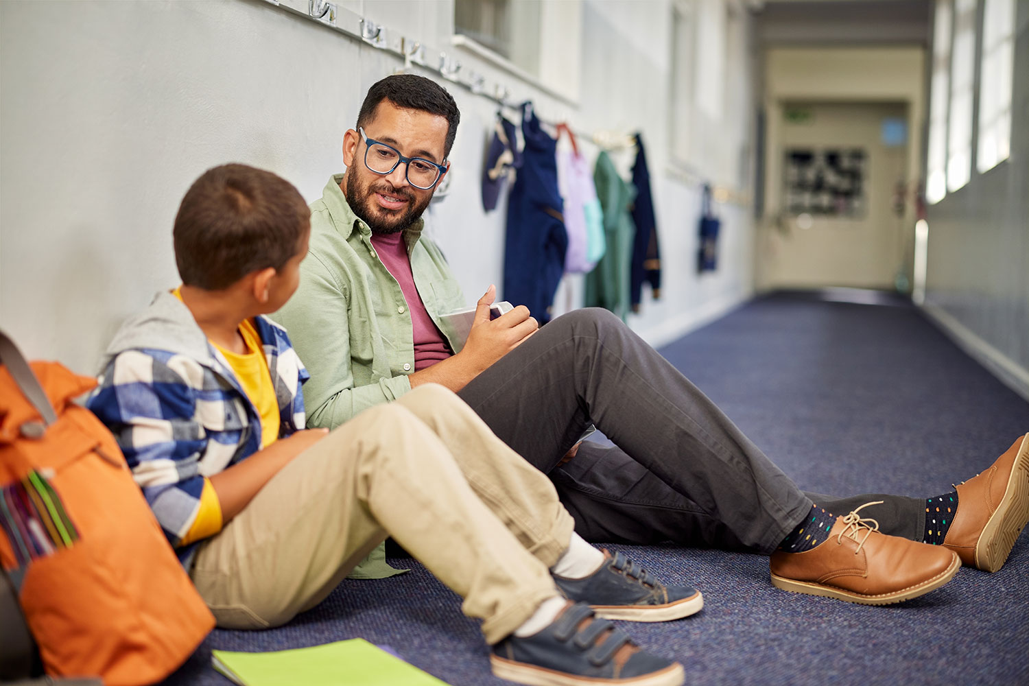 a man and boy sitting in a hallway talking