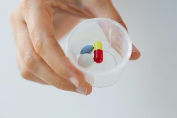 a person holding a cup with pills in it