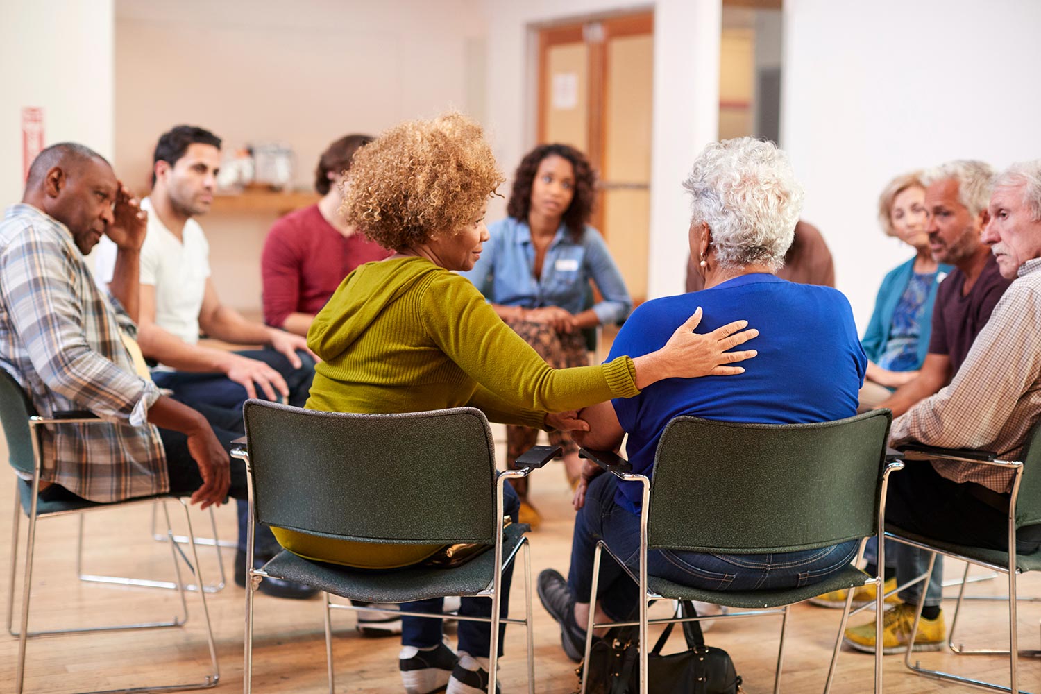 a group of people sitting in a circle supportively listening to one person talk