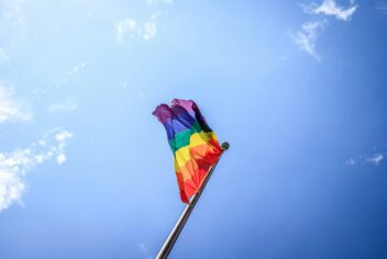 LGBTQ+ Flag waving with blue sky in background