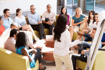 a group of adults listen while a person presents with a flip chart