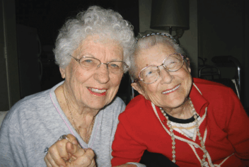 two women smiling and holding hands