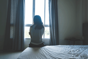 a woman sitting on a bed viewed from behind