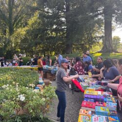people outside looking at books on tables